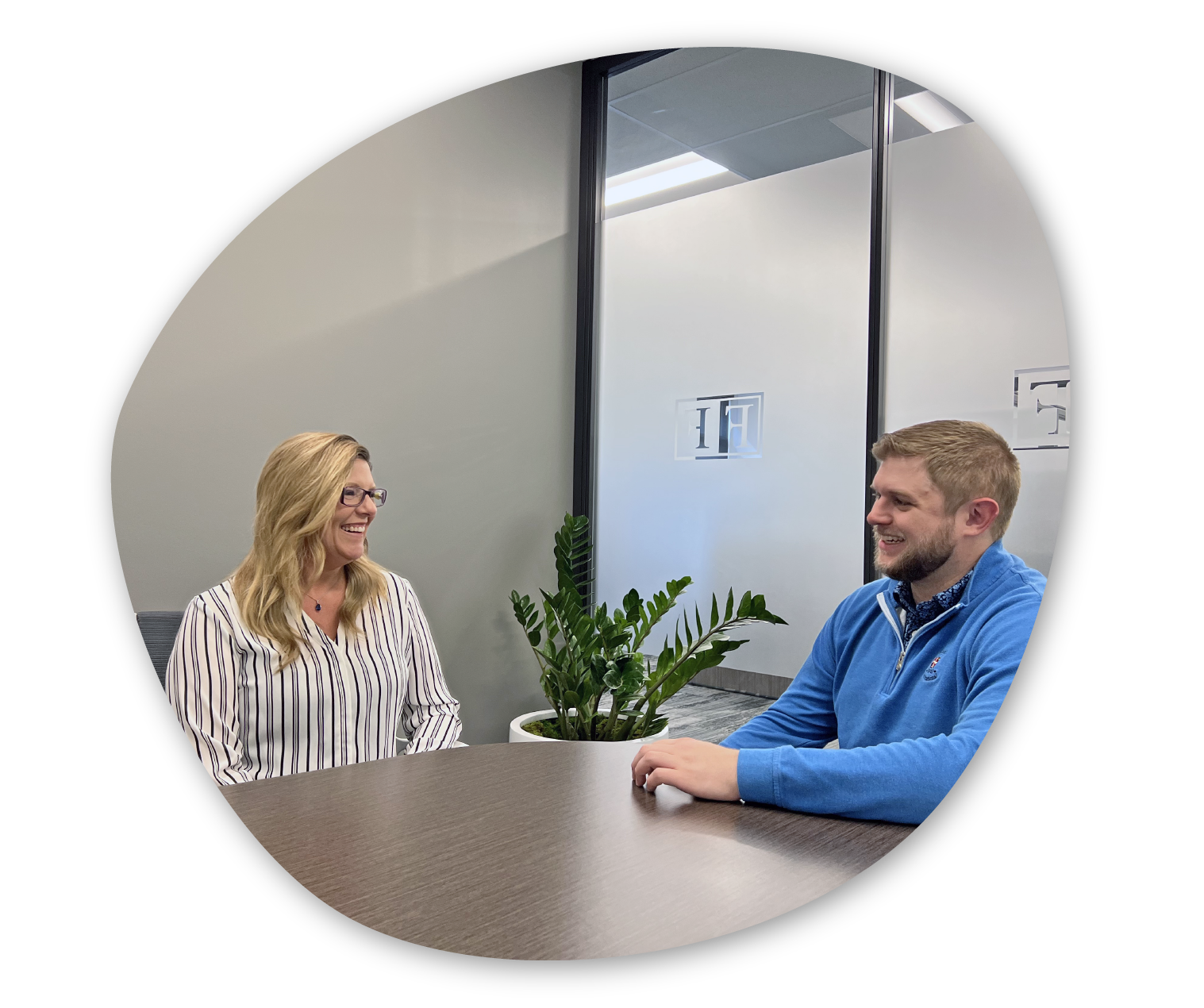 Founders administrative support team members in meeting space with plant and frosted glass smiling